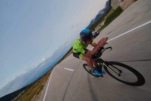 triathlon athlete riding professional racing bike at workout on curvy country road