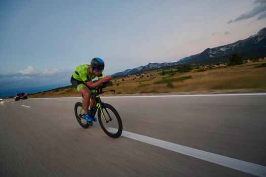 triathlon athlete riding professional racing bike at workout on curvy country road