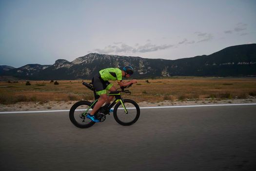 triathlon athlete riding professional racing bike at workout on curvy country road