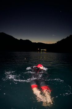 triathlon swimmer have extreme training  on dark night wearing wetsuit concept of strength and endurance