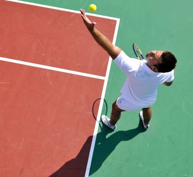 young man play tennis outdoor on orange tennis court at early morning