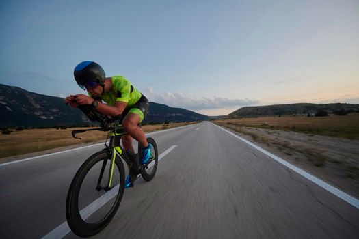 triathlon athlete riding professional racing bike at workout on curvy country road