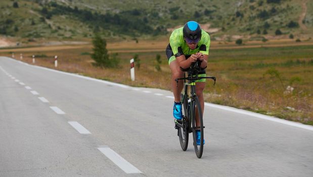 triathlon athlete riding professional racing bike at workout on curvy country road