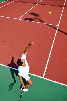 young man play tennis outdoor on orange tennis court at early morning