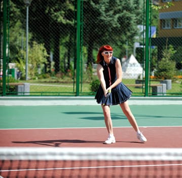 young fit woman play tennis outdoor on orange tennis field at early morning