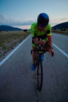 triathlon athlete riding professional racing bike at night workout on curvy country road w