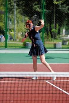 young fit woman play tennis outdoor on orange tennis field at early morning