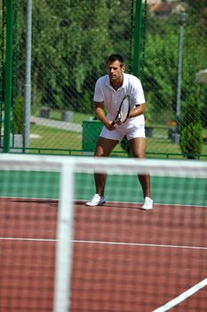 young man play tennis outdoor on orange tennis field at early morning