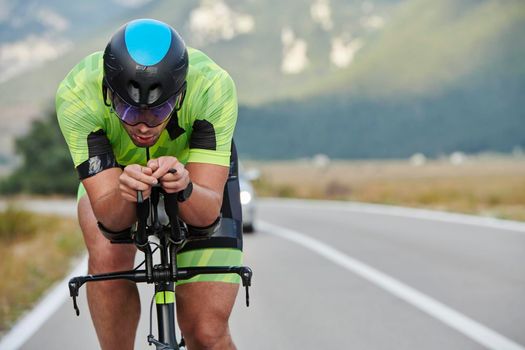 triathlon athlete riding professional racing bike at workout on curvy country road