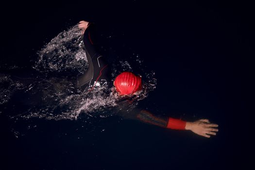 triathlon swimmer have extreme training  on dark night wearing wetsuit concept of strength and endurance