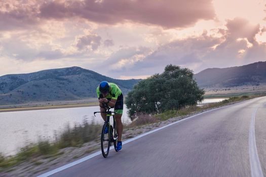 triathlon athlete riding professional racing bike at workout on curvy country road