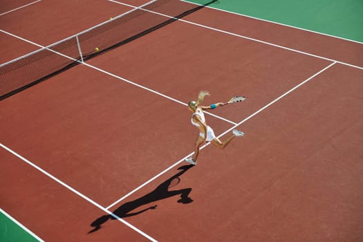 young fit woman play tennis outdoor on orange tennis field at early morning 