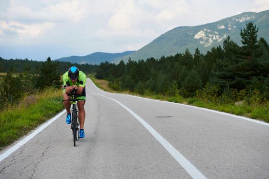 triathlon athlete riding professional racing bike at workout on curvy country road