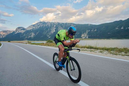 triathlon athlete riding professional racing bike at workout on curvy country road