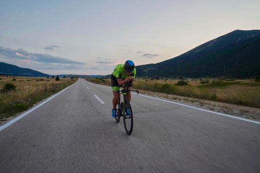 triathlon athlete riding professional racing bike at workout on curvy country road