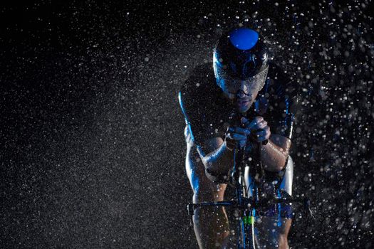 triathlon athlete riding professional racing bike fast  at night with bad weather and falling rain