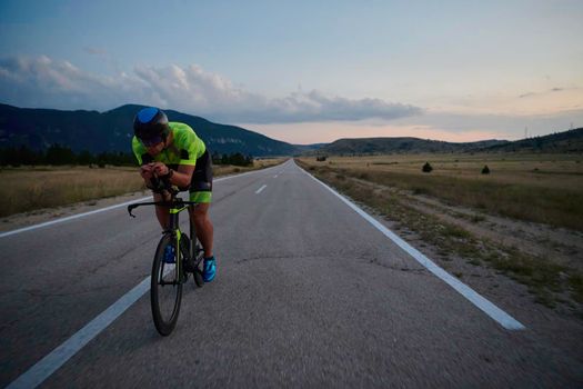 triathlon athlete riding professional racing bike at night workout on curvy country road w