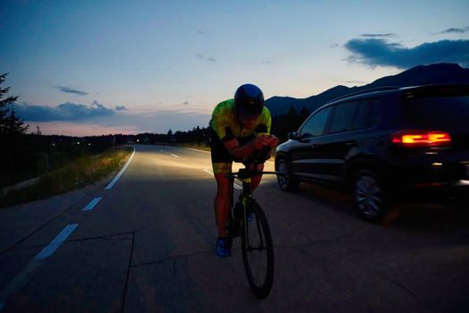 triathlon athlete riding professional racing bike at night workout on curvy country road w