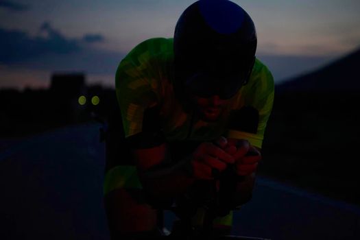 triathlon athlete riding professional racing bike at night workout on curvy country road w