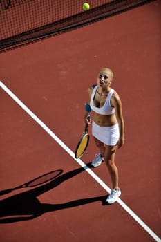 young fit woman play tennis outdoor on orange tennis field at early morning