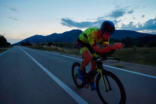 triathlon athlete riding professional racing bike at night workout on curvy country road w