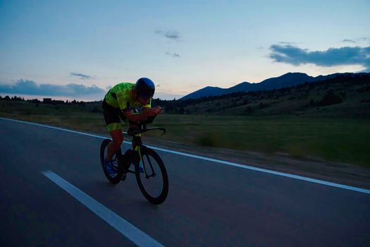 triathlon athlete riding professional racing bike at night workout on curvy country road w