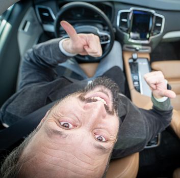 Funny wide angle of a male driver in luxury car