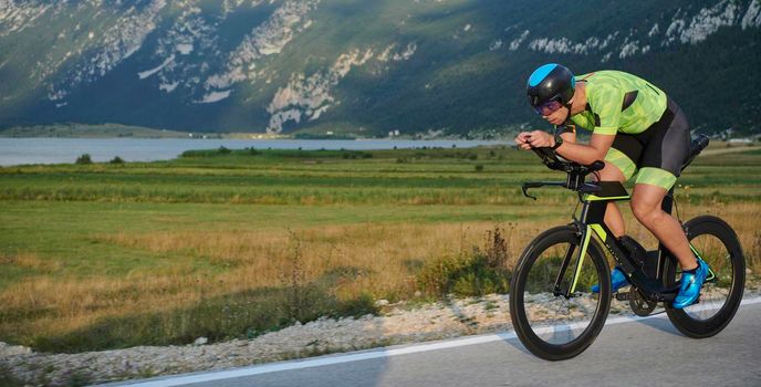 triathlon athlete riding professional racing bike at workout on curvy country road