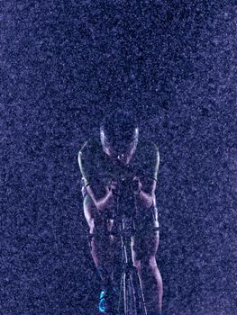 triathlon athlete riding professional racing bike at night with bad weather and falling rain