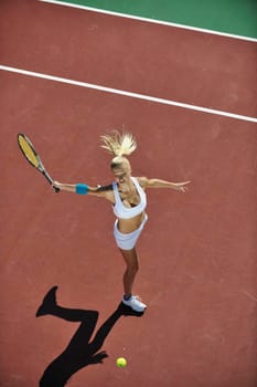 young fit woman play tennis outdoor on orange tennis field at early morning 