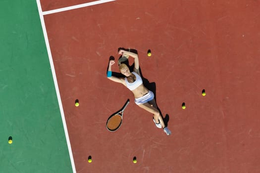 young fit woman play tennis outdoor on orange tennis field at early morning