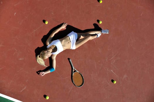 young fit woman play tennis outdoor on orange tennis field at early morning