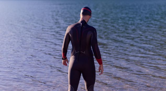 reak triathlon athlete getting ready and prepare goggles hat and  wetsuit for swimming training on lake