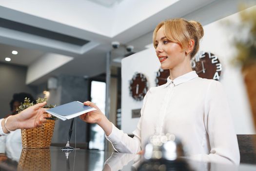 Hotel receptionist woman takes guest's passport for check in close up