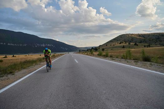 triathlon athlete riding professional racing bike at workout on curvy country road