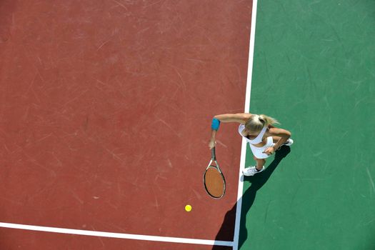 young fit woman play tennis outdoor on orange tennis field at early morning