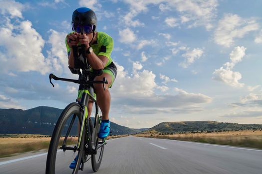 triathlon athlete riding professional racing bike at workout on curvy country road