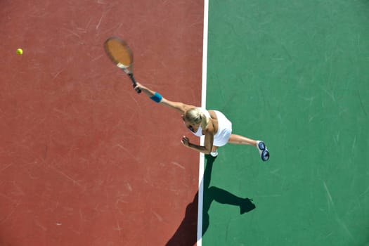 young fit woman play tennis outdoor on orange tennis field at early morning