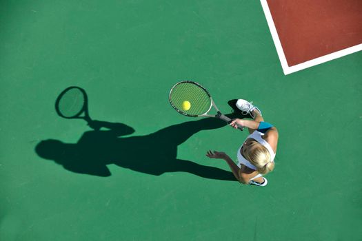 young fit woman play tennis outdoor on orange tennis field at early morning