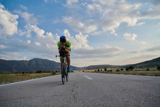 triathlon athlete riding professional racing bike at workout on curvy country road