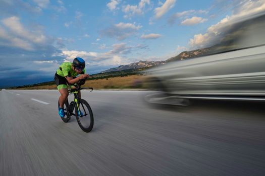 triathlon athlete riding professional racing bike at workout on curvy country road