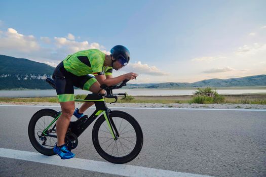 triathlon athlete riding professional racing bike at workout on curvy country road