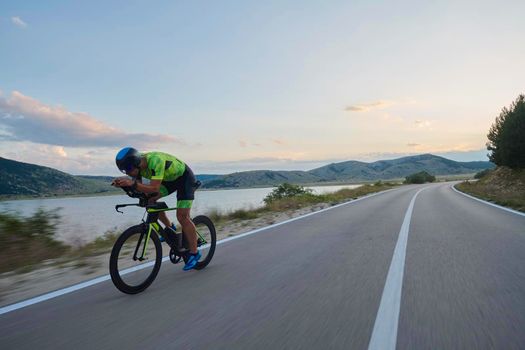 triathlon athlete riding professional racing bike at workout on curvy country road