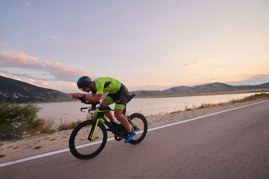 triathlon athlete riding professional racing bike at workout on curvy country road