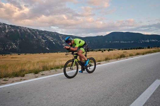 triathlon athlete riding professional racing bike at workout on curvy country road