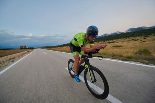 triathlon athlete riding professional racing bike at workout on curvy country road