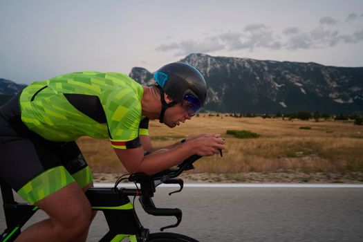 triathlon athlete riding professional racing bike at workout on curvy country road