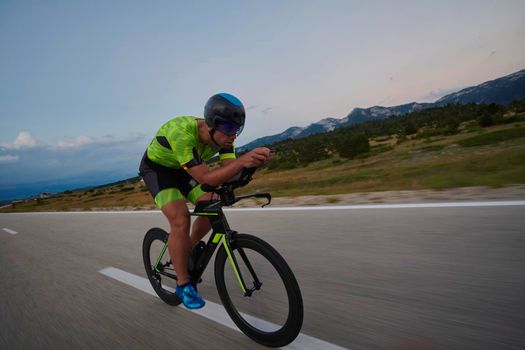 triathlon athlete riding professional racing bike at workout on curvy country road