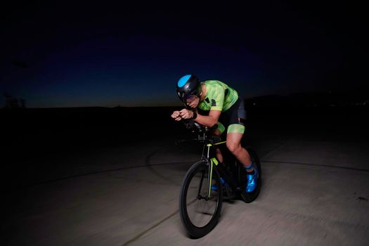 triathlon athlete cycling fast riding professional racing bike at night