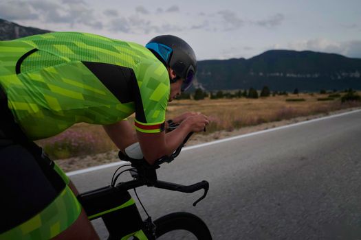 triathlon athlete riding professional racing bike at workout on curvy country road